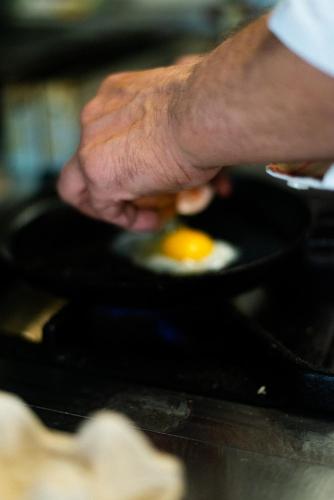 a person holding an egg in a frying pan at Hotel De Nac in Nago-Torbole