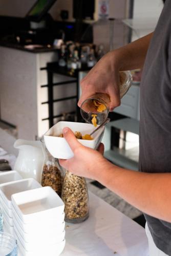 a person is putting food into a bowl at Hotel De Nac in Nago-Torbole