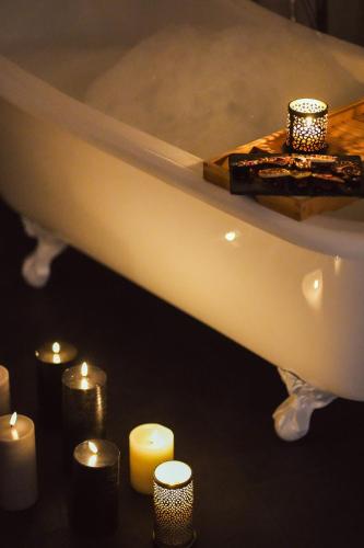 a bath tub with candles and a group of candles at Hotel Le Lion D'Or et Restaurant La Table Du Lion in Bayeux