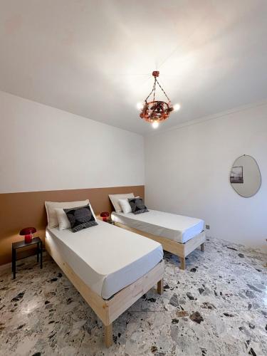 a bedroom with two beds and a chandelier at Borgo Design Apartment by the sea in Civitavecchia