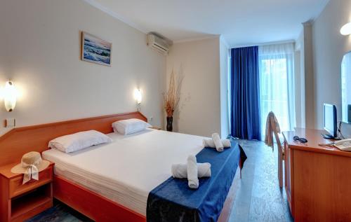 a bedroom with a bed and a desk and a television at Семеен хотел Амон Ра in Sozopol