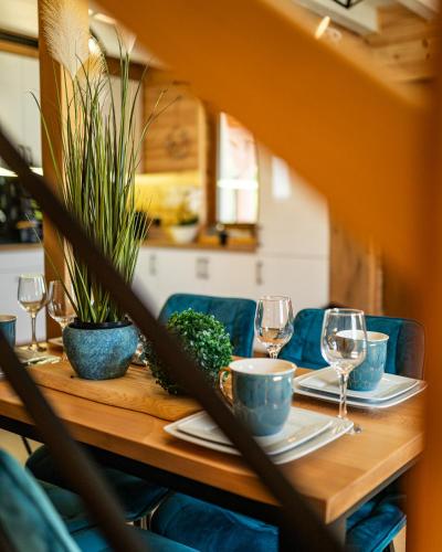 a wooden table with plates and glasses and plants at Perła Kaszub in Wiele