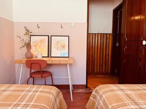 a bedroom with two beds and a table with a chair at Casa do Lambril in Tinalhas