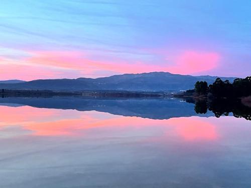 a view of a lake at sunset with mountains in the background at Casa do Lambril in Tinalhas