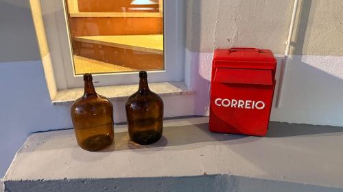 two bottles sitting next to a window next to a red box at Casa do Lambril in Tinalhas