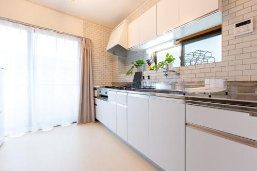 a kitchen with white counters and a large window at Vacation Rental -Nagumo301- in Tokyo