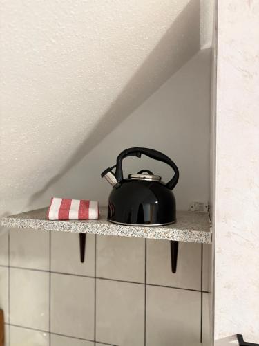 バート・フュッシンクにあるAppartementshaus Vlora 2 App 7のキッチンの棚に置かれた黒いティーケトル