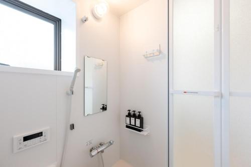 bagno bianco con doccia e specchio di Vacation Rental -Nagumo301- a Tokyo