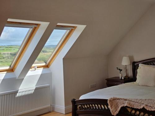 a bedroom with two windows and a bed at Fiáin Retreat in Miltown Malbay