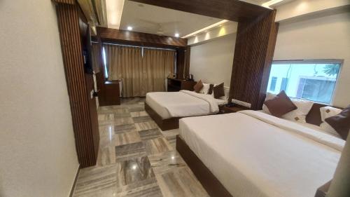 a hotel room with two beds and a window at Hotel Vrindavan Nashik in Nashik
