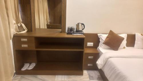 a bedroom with a dresser next to a bed at Hotel Vrindavan Nashik in Nashik