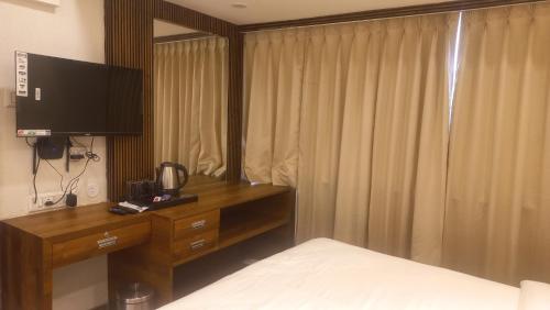 a bedroom with a bed and a desk with a television at Hotel Vrindavan Nashik in Nashik