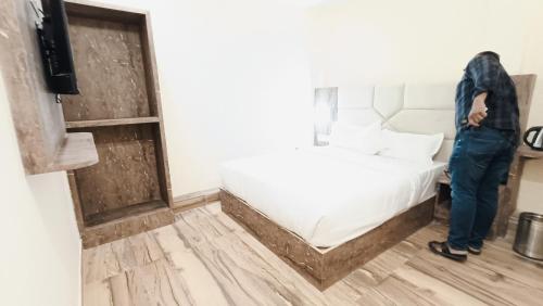 a man standing next to a bed in a room at Hotel Richie Residency in Mumbai