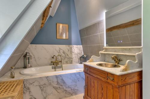 a bathroom with a sink and a bath tub at La maison du fermier in Saint-Wandrille-Rançon