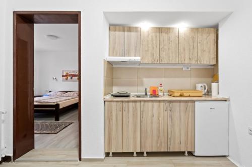 a kitchen with wooden cabinets and a room with a bed at Apartmani Sokobanja Alexandar in Soko Banja