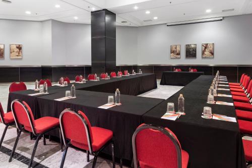 a conference room with long tables and red chairs at Melia Maria Pita in A Coruña