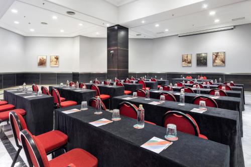 a conference room with black tables and red chairs at Melia Maria Pita in A Coruña
