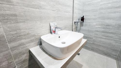 a white bathroom with a sink and a shower at Sans Vibes Hotel Damai Yogyakarta in Kejayan