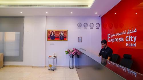 un hombre sentado en un escritorio en el vestíbulo en Express City Hotel - Duqm, en Duqm