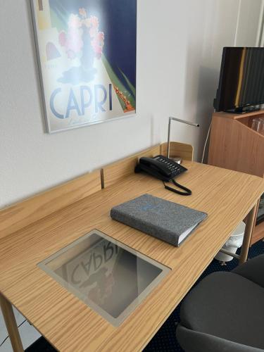 a wooden desk with a keyboard and a phone on it at Hotel Capri in Überlingen