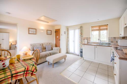 a kitchen and living room with a couch and a table at The Cartlodge Boundary Farm, Framlingham in Woodbridge