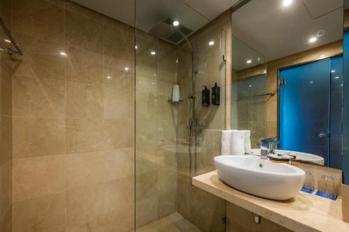 a bathroom with a sink and a glass shower at Marins Suites - Adults Only Hotel in Cala Millor
