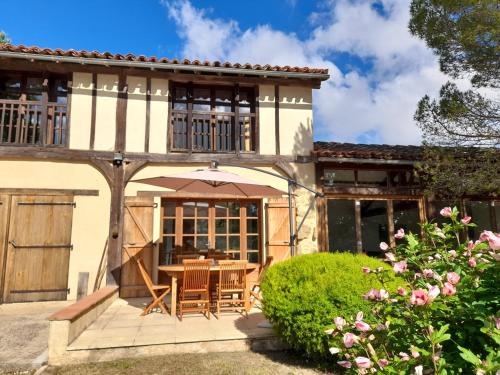 an external view of a house with a table and chairs at Maison Loumagne - Gîte près de Marciac in Monlezun