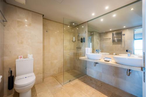 a bathroom with two sinks and a shower and a toilet at Marins Suites - Adults Only Hotel in Cala Millor