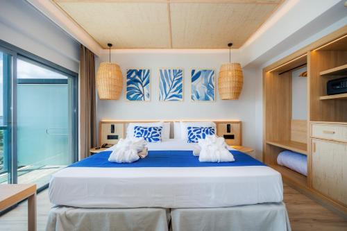 a bedroom with a large bed with blue and white pillows at Marins Suites - Adults Only Hotel in Cala Millor