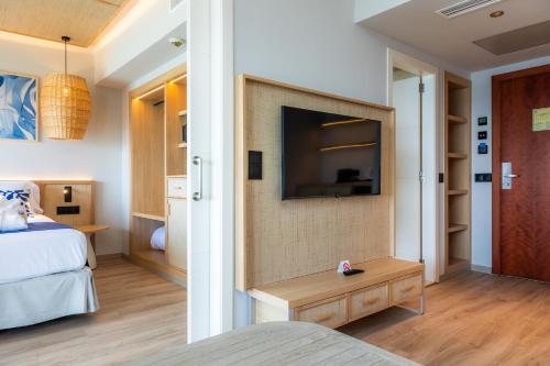 a bedroom with a bed and a tv on a wall at Marins Suites - Adults Only Hotel in Cala Millor