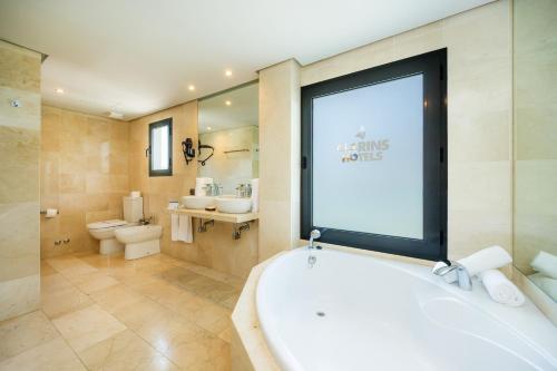 a bathroom with a tub and a large window at Marins Suites - Adults Only Hotel in Cala Millor