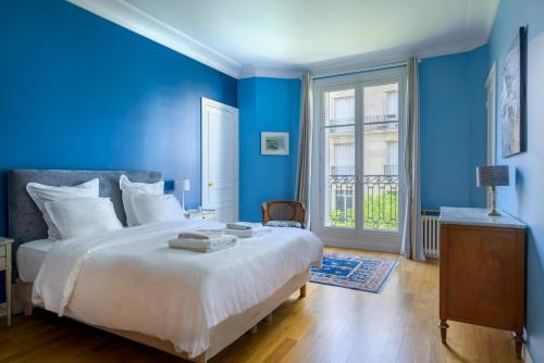 - une chambre bleue avec un grand lit et une fenêtre dans l'établissement Paris Palais des Congrès Residence, à Neuilly-sur-Seine