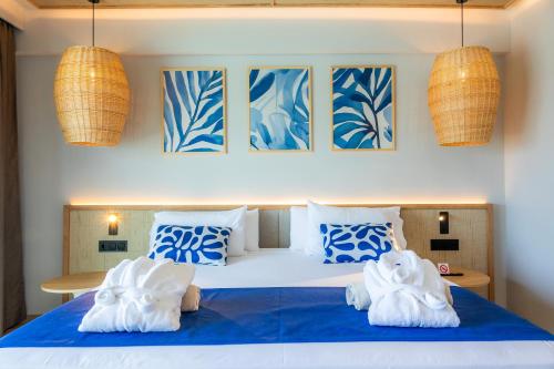 a bedroom with a bed with blue and white pillows at Marins Suites - Adults Only Hotel in Cala Millor