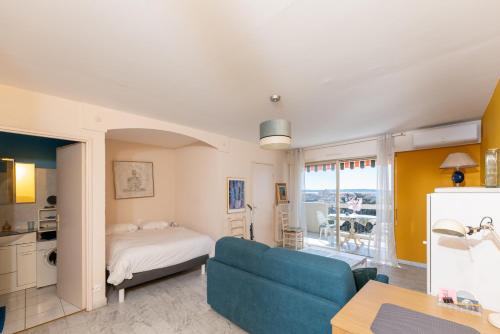 a bedroom with a bed and a couch and a kitchen at L'estivalière in Golfe-Juan