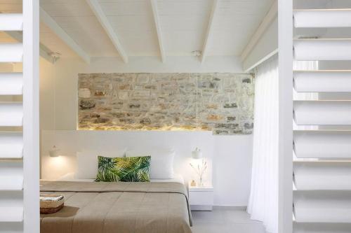 a bedroom with a bed and a stone wall at Makryammos in Limenas