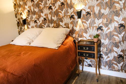 a bedroom with a bed and a table with a pillow at Les Rêveries de Tinténiac in Tinténiac