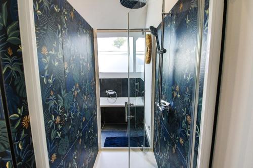 a bathroom with a shower with blue wallpaper at Les Rêveries de Tinténiac in Tinténiac