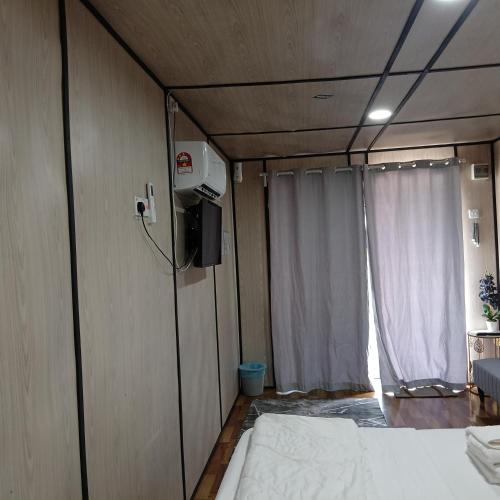 a room with a bed and a tv and a curtain at Chinta chinta cottage kabin 2 in Arau
