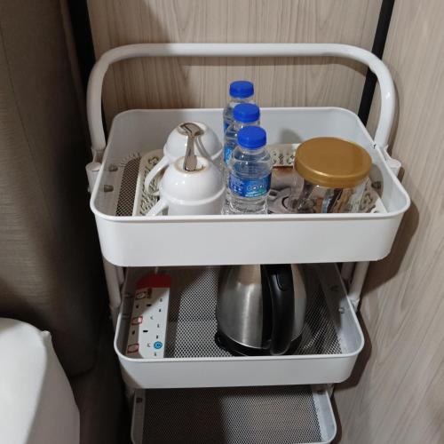 a shelf with water bottles and other items in a room at Chinta chinta cottage kabin 2 in Arau