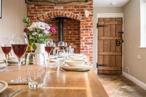 a table with glasses of wine and a brick wall at The Farmhouse Boundary Farm Framlingham in Woodbridge