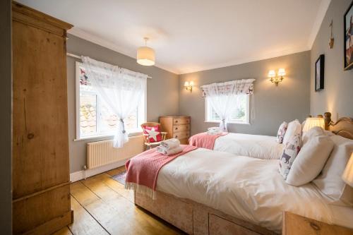 a bedroom with two beds and a window at The Farmhouse Boundary Farm Framlingham in Woodbridge