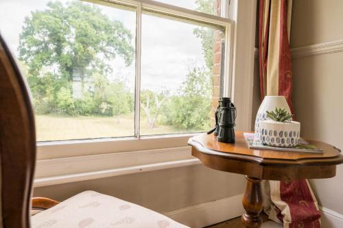 a table with a cake on it next to a window at The Farmhouse Boundary Farm Framlingham in Woodbridge