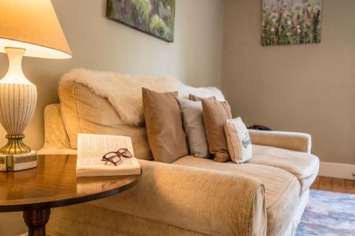 a living room with a couch and a table with a book at The Farmhouse Boundary Farm Framlingham in Woodbridge