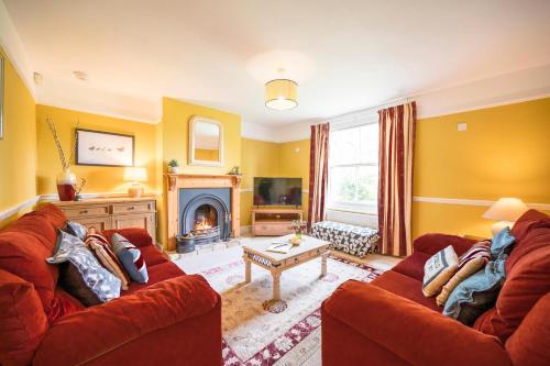 a living room with two red couches and a fireplace at The Farmhouse Boundary Farm Framlingham in Woodbridge