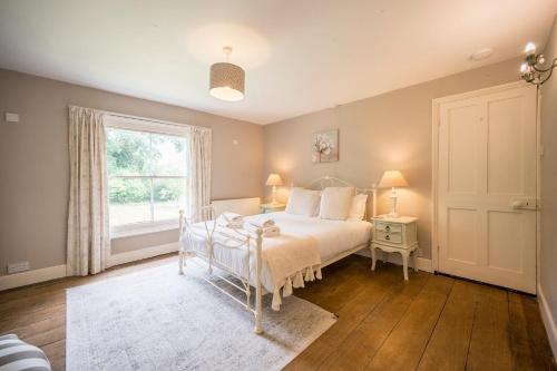 a bedroom with a white bed and a window at The Farmhouse Boundary Farm Framlingham in Woodbridge