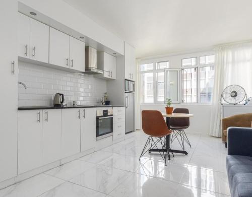 Una cocina con gabinetes blancos y una mesa y sillas. en Cozy nest in the town city, en Vosburg