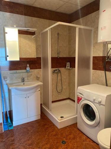 a bathroom with a shower and a sink and a washing machine at 2-комнатные апартаменты у моря 10 бассейнов Crown Fort Noks in Sveti Vlas