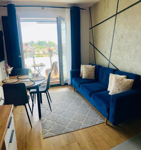 a living room with a blue couch and a table at Apartament Poznańska 1 in Suwałki