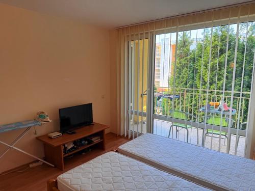 a bedroom with a bed and a television and a balcony at 2-комнатные апартаменты у моря 10 бассейнов Crown Fort Noks in Sveti Vlas