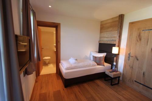 a bedroom with a white bed and a bathroom at Maierl-Alm & Maierl-Chalets in Kirchberg in Tirol